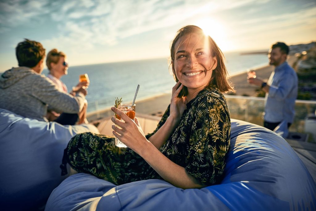 eine Frau trint und lacht am Rooftop Bar